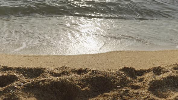 Seascape with Focus on Waves and Ocean Water with Blurry Beach Sand in the Foreground