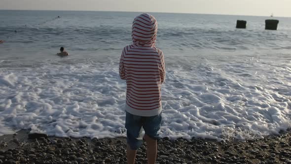 The Boy Stands on the Seashore and Looks at the Seascape