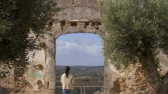 Caucasian woman traveler in Montemor o Novo stone castle ruin entrance gate of old church