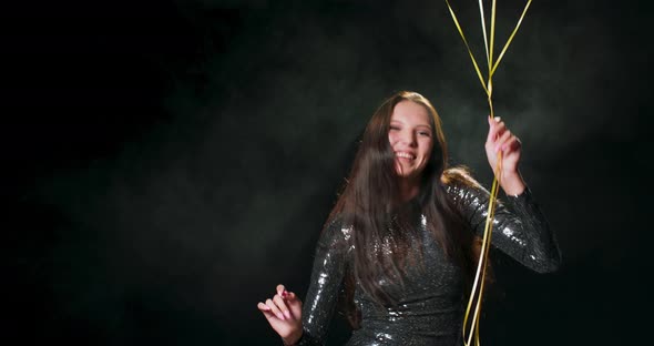 Woman Giving a Cheer for New Year A Woman in a Black Brocade Dress Dances While Holding Black and