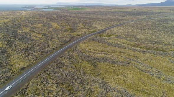 White Car on Road and Volcanic Lava Rock Formations. Iceland. Aerial View