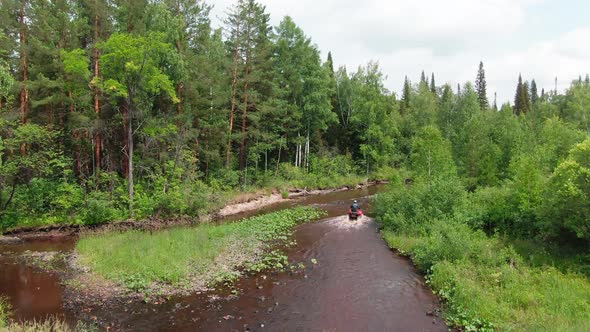 Drone Shot of Man Driving Four-Wheeler through River