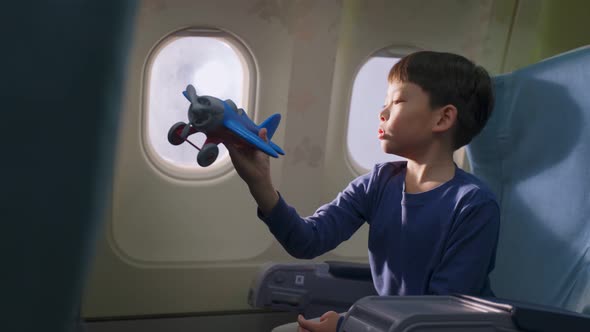 Asian young little boy playing aircraft model toy, sitting on airplane and dream about to be a pilot