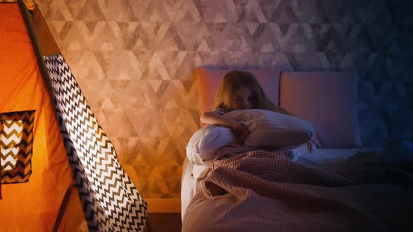 Distressed Little Girl Hugs Pillow and Breathes Hard on Bed