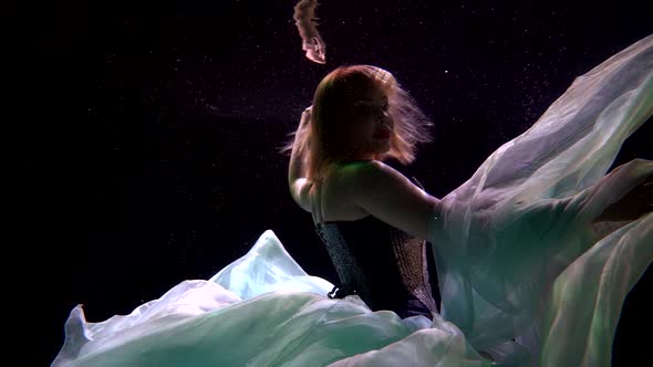 Sexy Busty Woman Is Floating Underwater, Playing with Chiffon Fabric of Her Dress