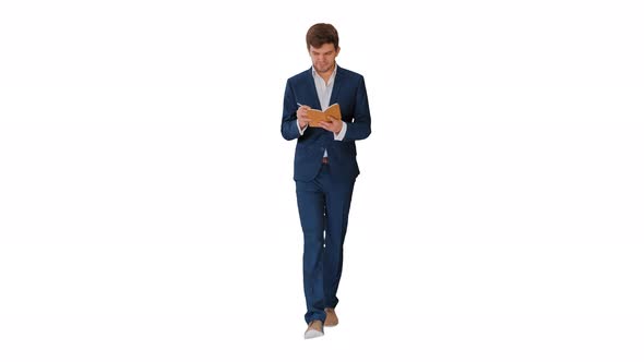 Young Businessman Thinking and Writing Notes in His Notebook While Walking on White Background