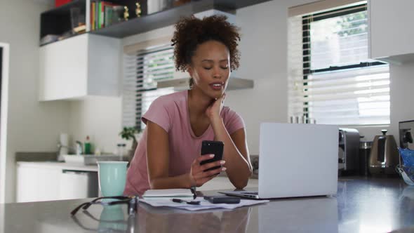 Mixed race woman in kitchen using laptop