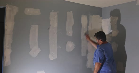 Contractor Using Sand Trowel Sanding the the Plaster Plasterboard