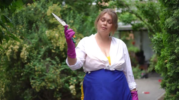Confident Woman Showing Prunning Scissors Gesturing Strength in Slow Motion Loooking at Camera