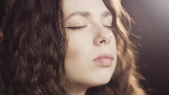 Close-up Portrait of a Young Curly Relaxing Woman Closing Her Eyes and Taking Deep Breath. Girl