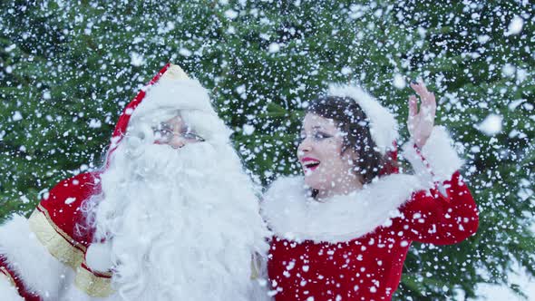 Santa Claus and Christmas girl enjoying the snowfall alt