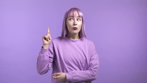 Portrait of Young Thinking Pondering Woman Having Idea Moment Pointing Finger Up on Violet Studio