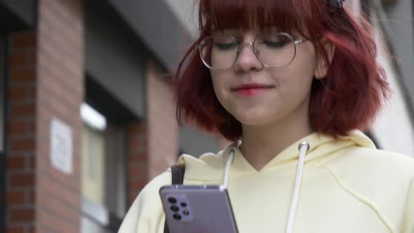 Young redhead Ukrainian teen girl with mobile phone on city street