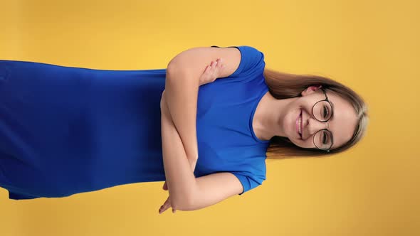 VERTICAL VIDEO POV Portrait Woman in Eyeglasses Posing with Crossed Hands Isolated on Orange Studio