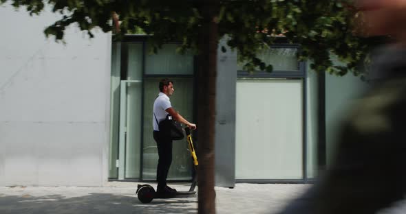 Side View of Businessman Riding Electric Scooter Along Pathway