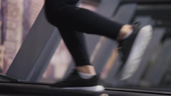 Side View Feet of Slim Young Woman Running on Treadmill