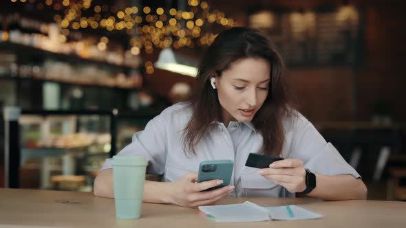 Young Woman Using Mobile and Credit Card at Cafe