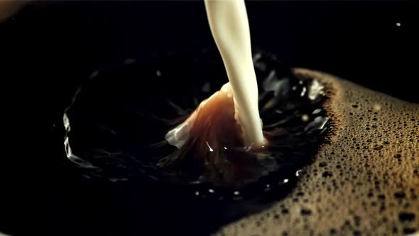 A Stream of Milk Pours Into the Black Coffee