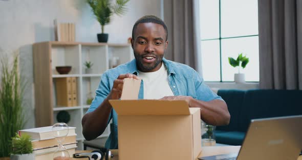 African American which Sitting in front of Camera During Unpacking Carton Box and Looking