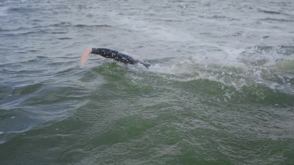 Professional Swimmer Triathlete in a Wetsuit Swims in Open Water Triathlon Competition Motion Blur