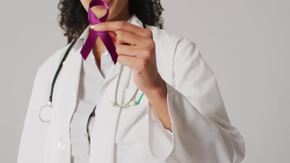 Video of smiling biracial female doctor holding purple pancreatic cancer ribbon