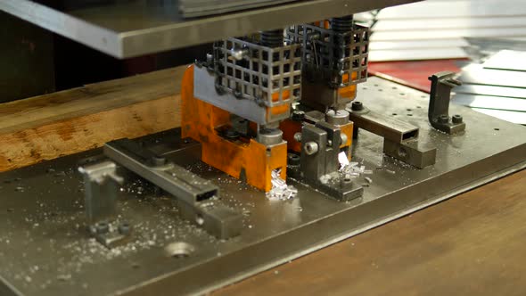 Worker making holes in metal plates with a punching drilling machine