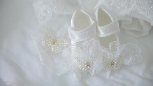 Little White Shoes with Pearls Lying on the Bed for Baby Girl