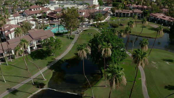 Aerial drone forwarding shot of Luxury Houses with pools alongside green golf course in Palm Springs