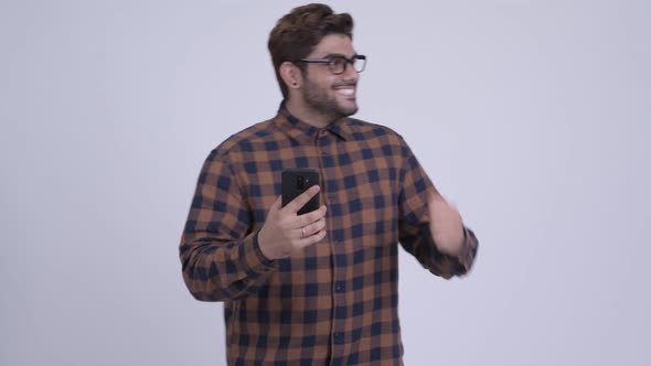 Happy Young Bearded Indian Hipster Man Using Phone and Getting Good News