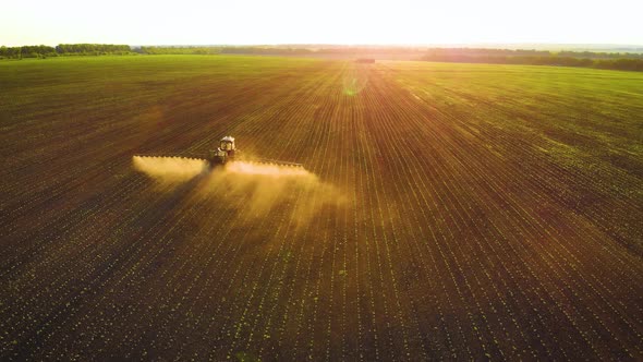 Aerial View of Farming Tractor Spraying on Field with Sprayer Herbicides and Pesticides at Sunset