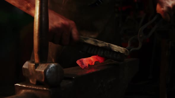 Mid-section of blacksmith using wire brush on hot iron