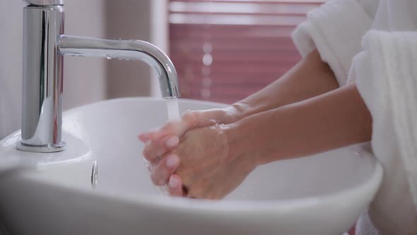 Closeup Female Hands Young Unrecognizable Woman Stands Near Washbasin in Bathrobe in Modern Bathroom