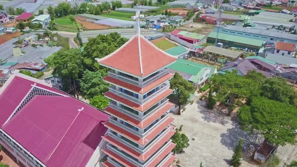 Drone Flies Over Modern Church Among Colorful Buildings Plants