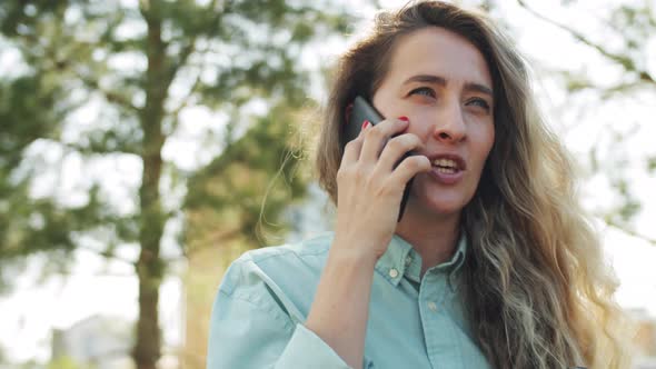 Woman Holding Coffee and Chatting on Phone Outdoors