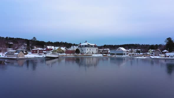 Aerial footage flying low over a skim of ice on east cove of Moosehead Lake towards snow covered dow