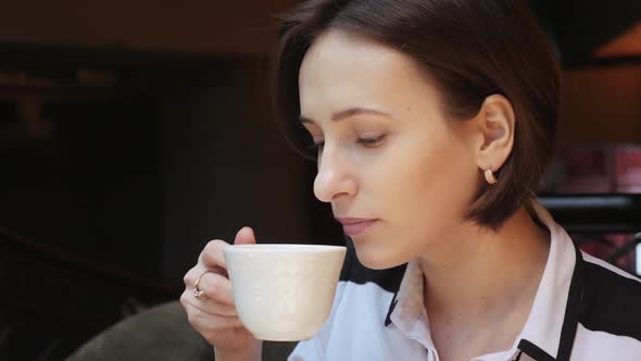Young Attractive Business Lady Drinking Coffee in Cozy Restaurant