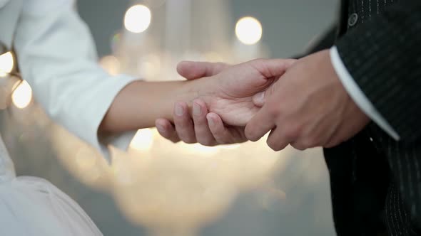 Man is Stroking Hand of His Beloved Bride in Wedding Day Closeup View Love and Tenderness