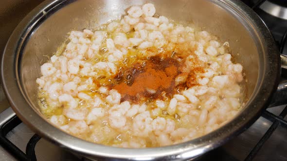 Mixing small fresh shrimps with bell pepper powder in steaming hot pot