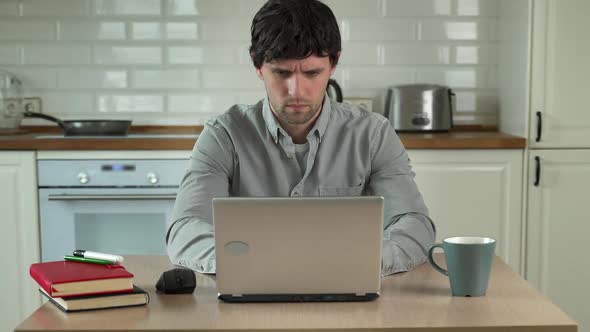 Young Man Works at Home on a Laptop in a Shirt Without Pants