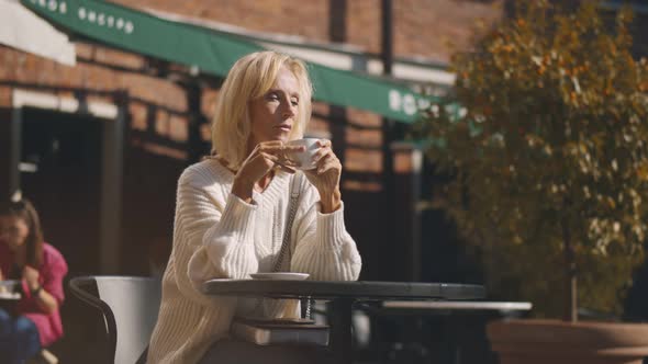 Happy Middle-aged Lady Relaxing with Coffee in Morning at Terrace Cafe