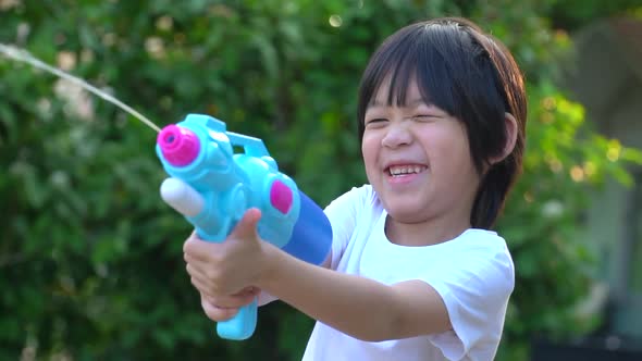 Cute Asian Child Playing With Water Gun In The Summer