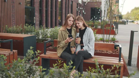 Twin Sisters Using Mobile Phone Outside