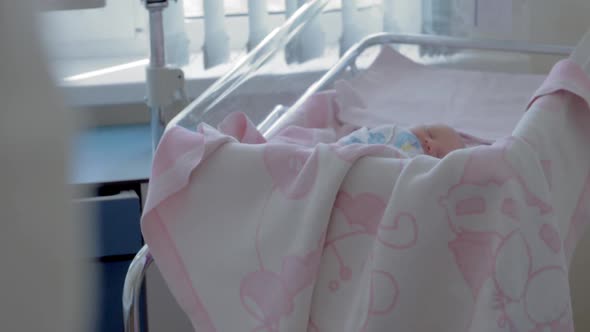 Newborn baby girl sleeping during her first days in maternity hospital