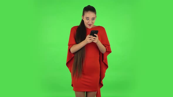 Pretty Young Woman Is Texting on Her Phone and Rejoicing. Green Screen