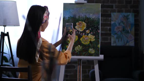 Female Painter Photographing Artwork with Peonies