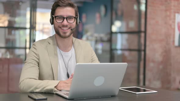 Man with Headset and Laptop Smiling at Camera