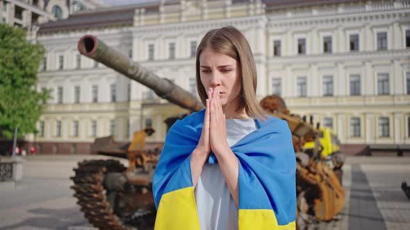 Ukrainian Woman Puts Hands in Prayer Standing Near Tank