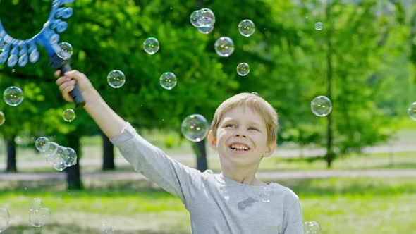 Playful Boy Swinging Wand and Making Soap Bubbles in Park alt