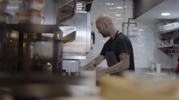 Blurry Objects in Foreground of Chef Working in Restaurant Kitchen