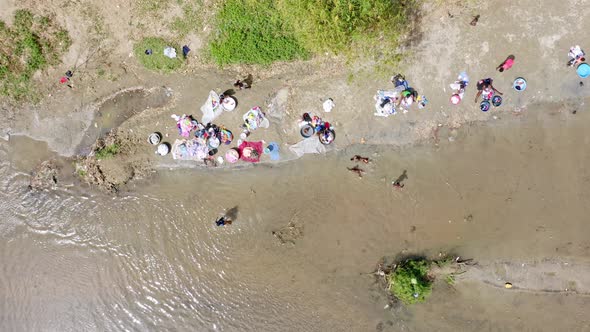 Children playing on shore while women wash clothes in Massacre river waters. Border between Haiti an